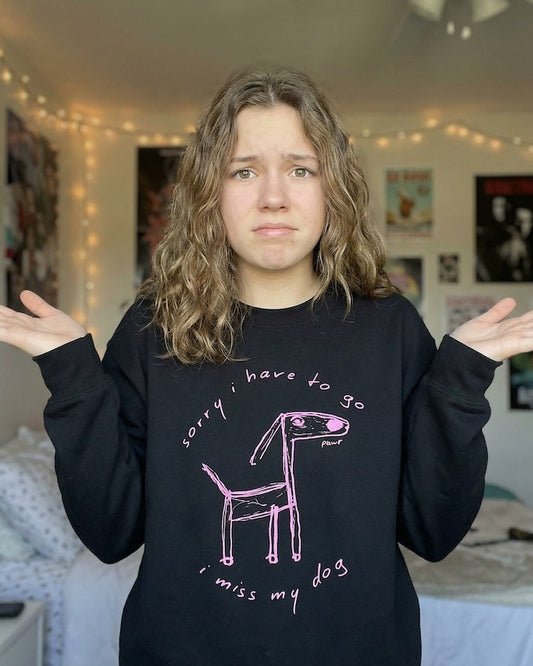 Person wearing a black dog lover sweatshirt with a hand-drawn dog illustration and the text “sorry i have to go i miss my dog,” expressing emotional dog owner humor and cozy PAWR dog apparel.