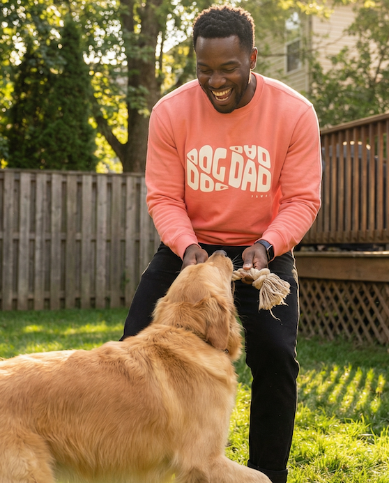 Man playing with a dog in a backyard wearing a dog dad shirt