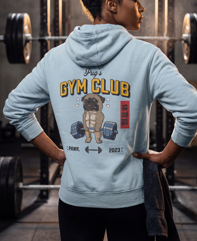 Person wearing a light blue hoodie with 'Pug's Gym Club' design in a gym setting