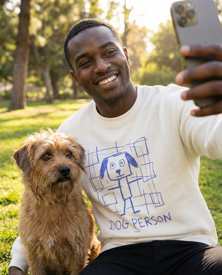 Man taking a selfie with a dog in a park wearing a 'Dog Person' shirt.