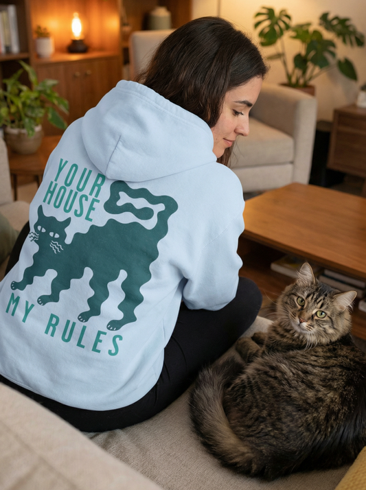 Woman wearing light blue cat hoodie with “Your House My Rules” funny cat graphic on back