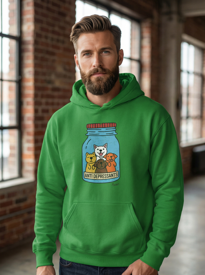 Bearded man wearing green Anti-Depressants dog hoodie with cartoon dog jar graphic standing in loft with brick walls and windows.