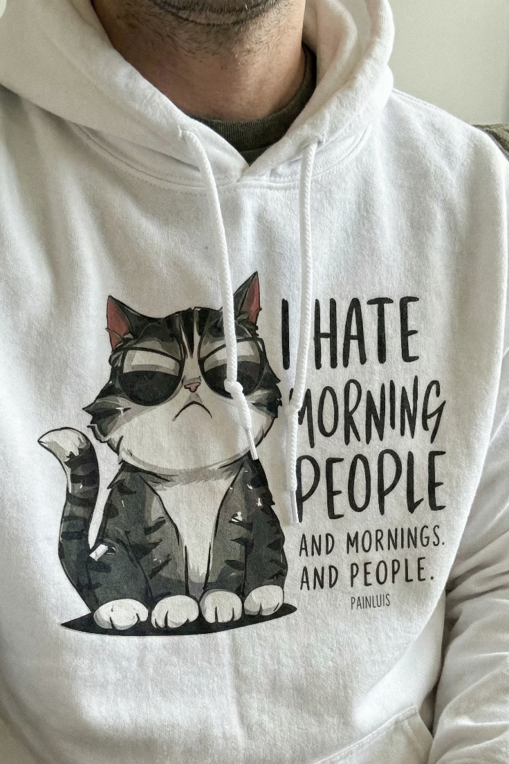 White hoodie with a cat graphic and text on a plain background
